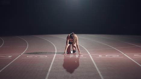 Die-Frau-Am-Start-Des-Rennens-Steigt-In-Die-Pads,-Erhebt-Sich-Und-Rennt-In-Zeitlupe-Abends-Im-Stadion.-Läuferin-Duckt-Sich-In-Die-Ausgangsposition,-Bevor-Sie-Mit-Dem-Rennen-Beginnt.